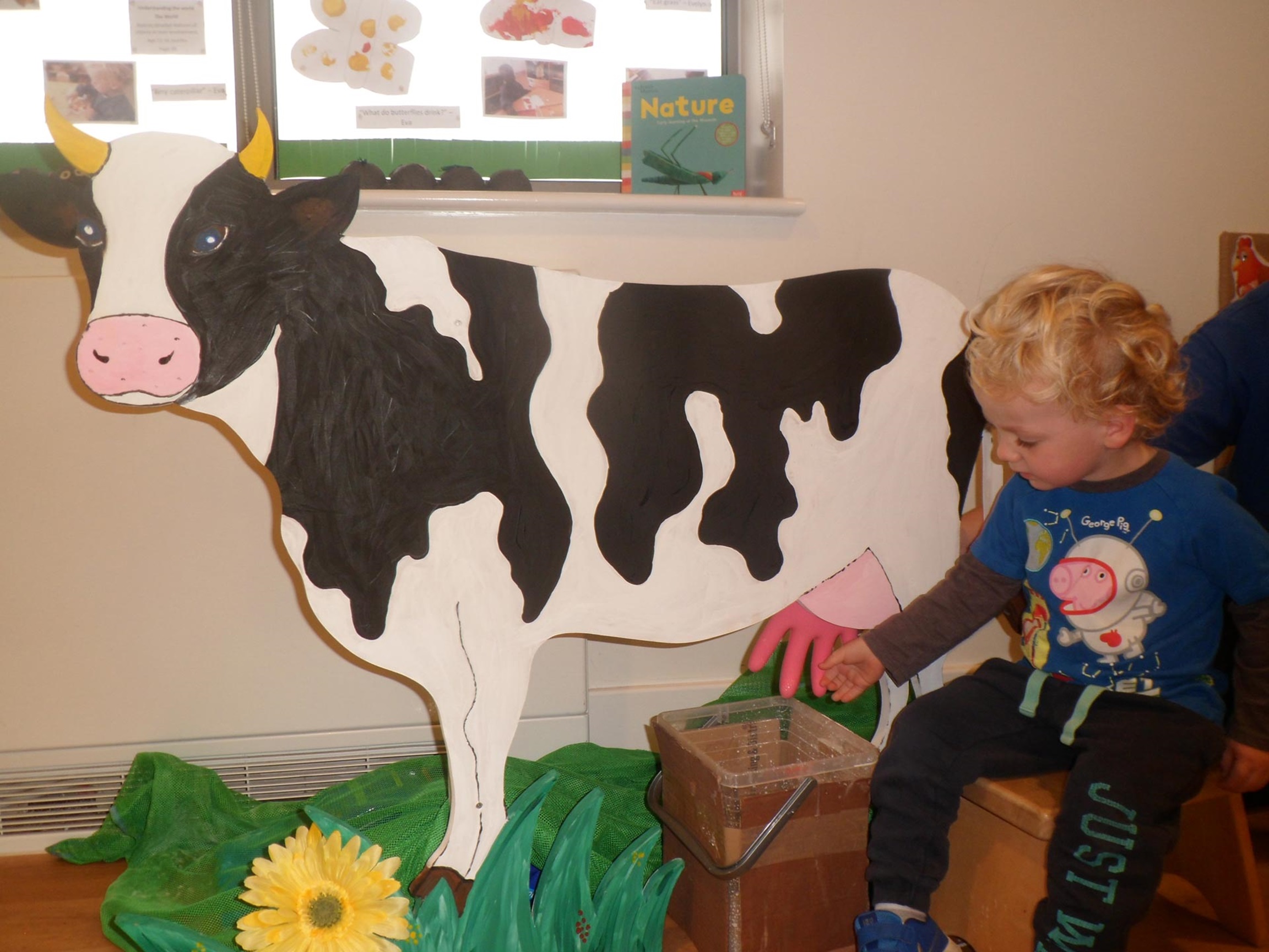 London nursery children practice milking a cow